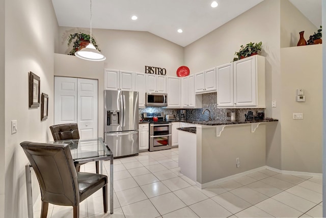 kitchen with decorative light fixtures, high vaulted ceiling, appliances with stainless steel finishes, kitchen peninsula, and white cabinets