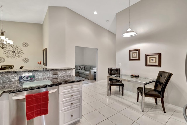 kitchen with pendant lighting, light tile patterned floors, white cabinetry, high vaulted ceiling, and stainless steel dishwasher