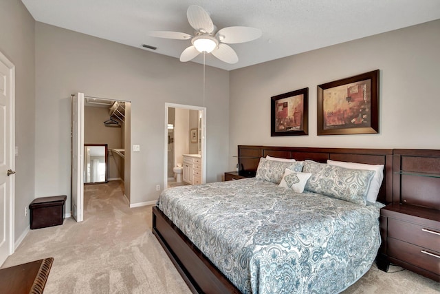 carpeted bedroom with a walk in closet, connected bathroom, ceiling fan, and a closet