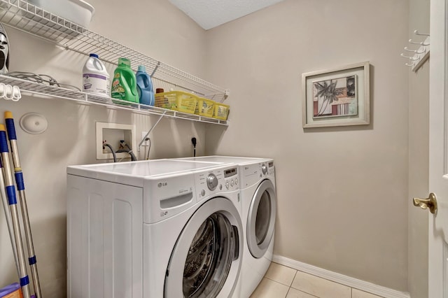 laundry area with light tile patterned floors, a textured ceiling, and independent washer and dryer