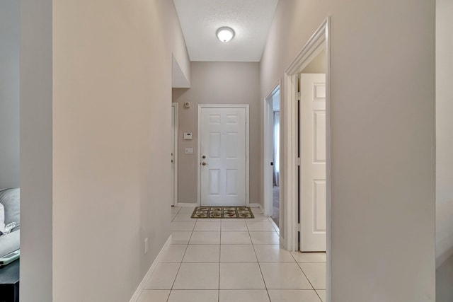 doorway to outside featuring light tile patterned floors and a textured ceiling