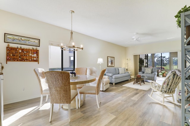 dining room with ceiling fan with notable chandelier and light wood-type flooring