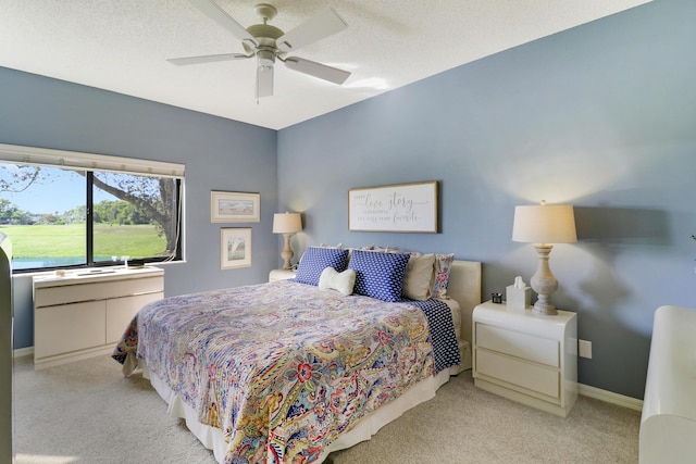 bedroom with ceiling fan, light carpet, and a textured ceiling