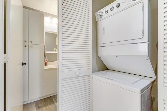 clothes washing area with stacked washing maching and dryer and light hardwood / wood-style flooring