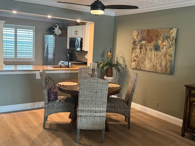 dining area with crown molding, sink, ceiling fan, and hardwood / wood-style flooring