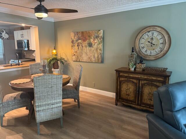 dining space featuring hardwood / wood-style flooring, ceiling fan, crown molding, and a textured ceiling