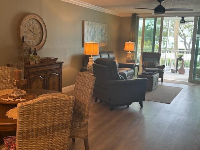 living room with a wealth of natural light, hardwood / wood-style floors, ceiling fan, and crown molding