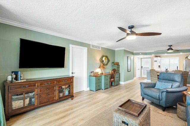 living room with light wood-type flooring, a textured ceiling, ceiling fan, and ornamental molding