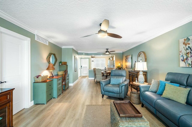 living room featuring light wood-type flooring, a textured ceiling, ceiling fan, and crown molding