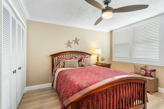 bedroom with ornamental molding, a textured ceiling, ceiling fan, light hardwood / wood-style floors, and a closet