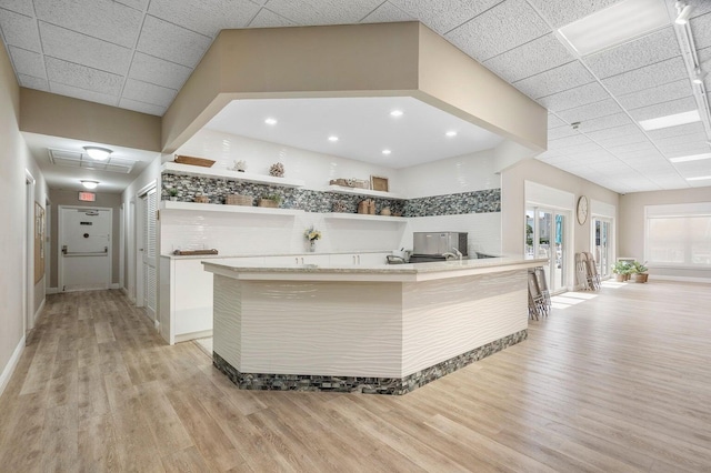 kitchen featuring stainless steel fridge, decorative backsplash, light hardwood / wood-style flooring, and white cabinets