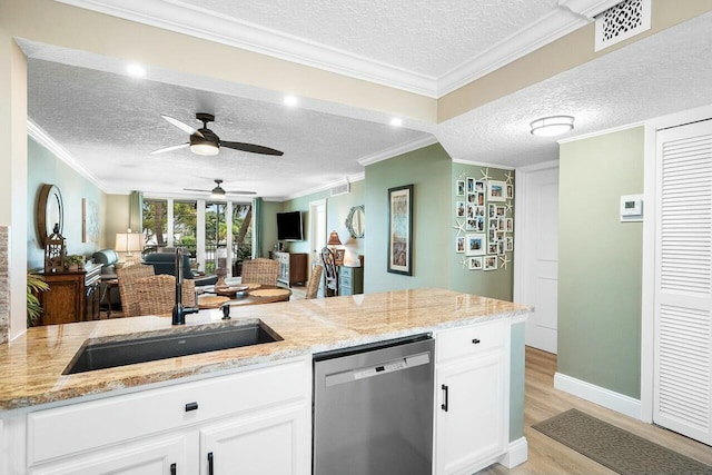 kitchen featuring light stone countertops, white cabinetry, stainless steel dishwasher, and sink