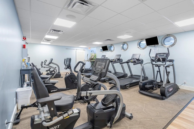 workout area with a paneled ceiling and light hardwood / wood-style floors