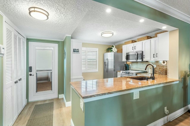 kitchen featuring kitchen peninsula, appliances with stainless steel finishes, white cabinetry, and sink