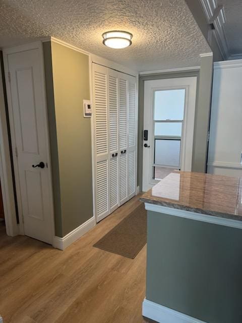 interior space featuring a textured ceiling, crown molding, and light hardwood / wood-style flooring