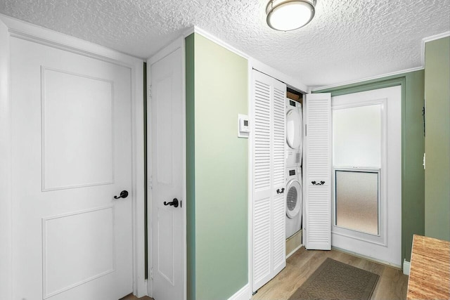 laundry area with stacked washer and dryer, a textured ceiling, and hardwood / wood-style flooring