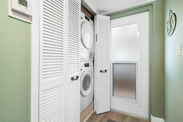 laundry area featuring stacked washer / drying machine and light wood-type flooring