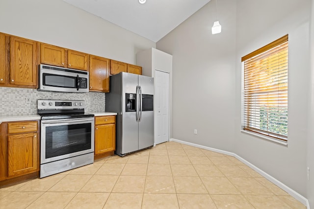 kitchen featuring tasteful backsplash, high vaulted ceiling, decorative light fixtures, light tile patterned floors, and appliances with stainless steel finishes