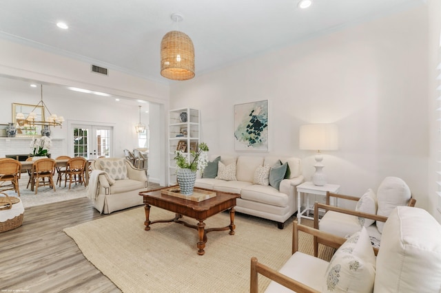 living room featuring crown molding, french doors, an inviting chandelier, and hardwood / wood-style flooring