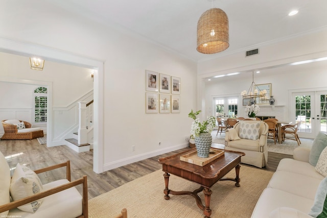 living room featuring ornamental molding, light hardwood / wood-style flooring, and french doors