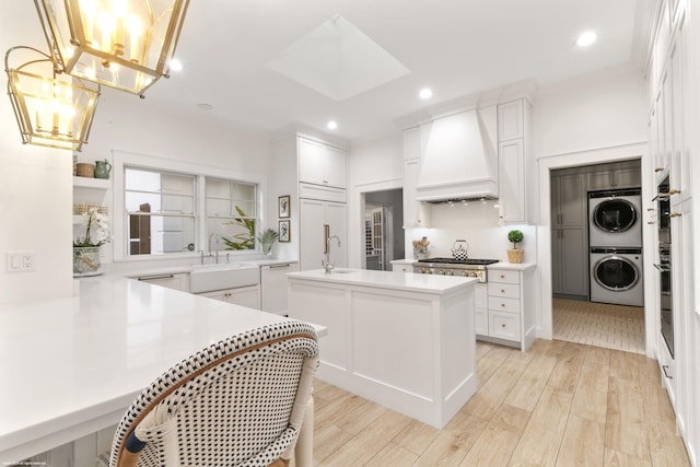 kitchen with white cabinets, stacked washer and dryer, premium range hood, and kitchen peninsula