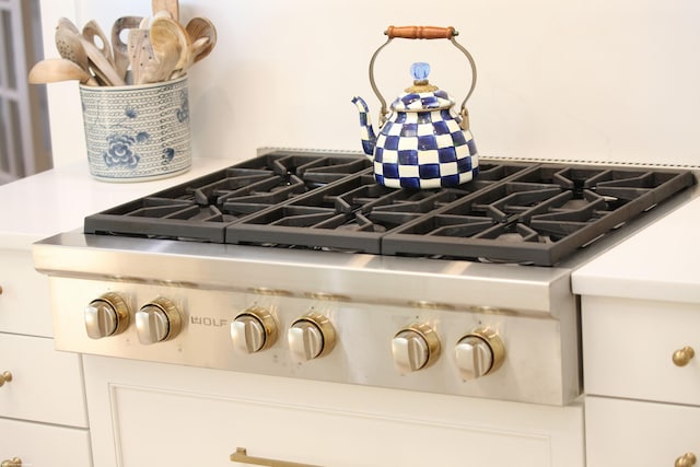 details with white cabinets, stainless steel gas stovetop, and backsplash