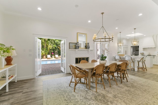 dining area with a brick fireplace, sink, ornamental molding, and hardwood / wood-style flooring