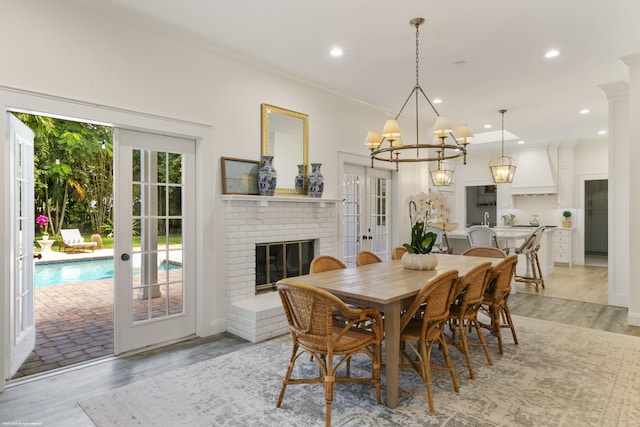 dining room with french doors, light hardwood / wood-style flooring, ornamental molding, and a brick fireplace