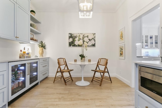 dining space with light hardwood / wood-style floors, wine cooler, crown molding, and a notable chandelier