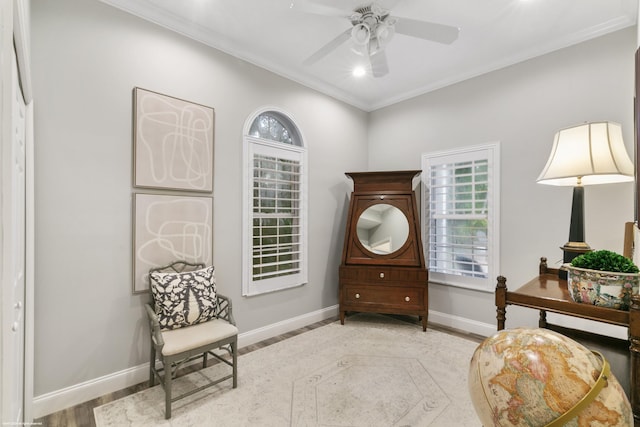 sitting room with ceiling fan, light wood-type flooring, and crown molding