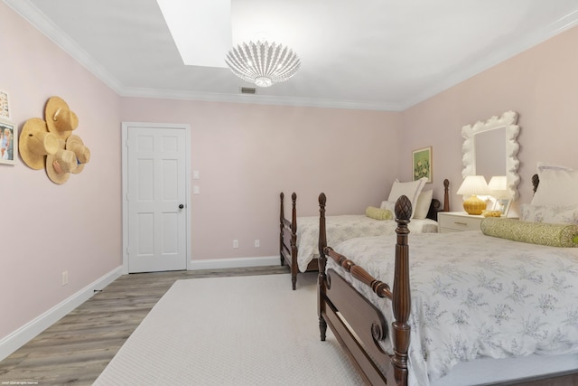 bedroom with hardwood / wood-style flooring, a notable chandelier, and ornamental molding