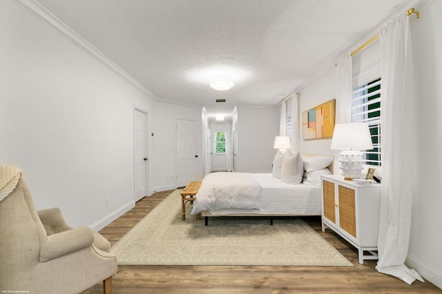 bedroom featuring a textured ceiling, wood-type flooring, and crown molding