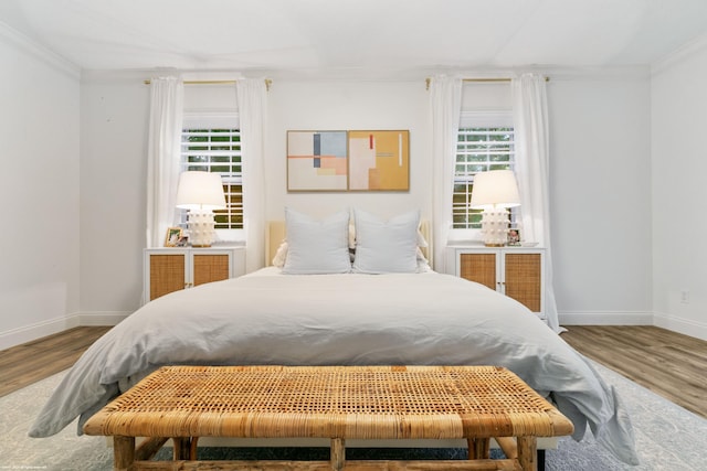 bedroom with wood-type flooring, multiple windows, and ornamental molding