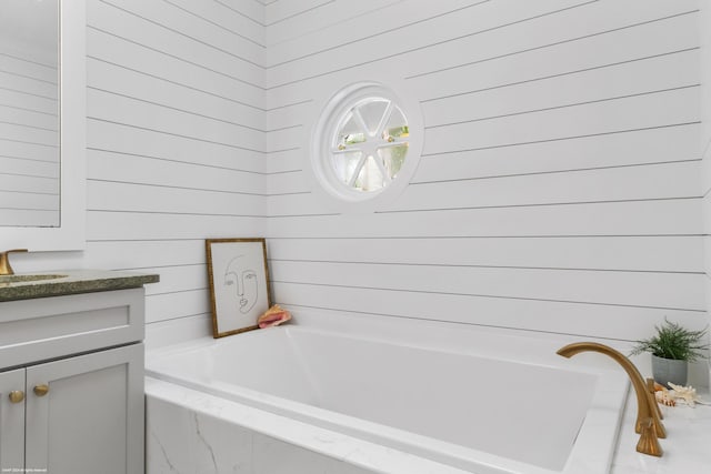 bathroom featuring vanity and tiled bath