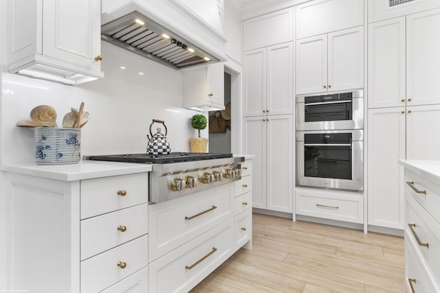 kitchen with light hardwood / wood-style flooring, stainless steel appliances, white cabinetry, and custom exhaust hood