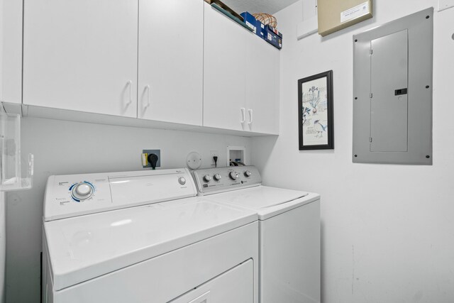 clothes washing area with electric panel, washer and dryer, and cabinets