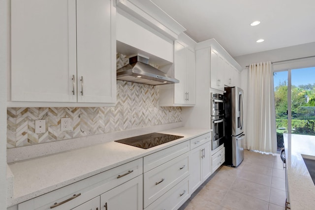 kitchen with wall chimney exhaust hood, stainless steel appliances, tasteful backsplash, light stone counters, and white cabinets