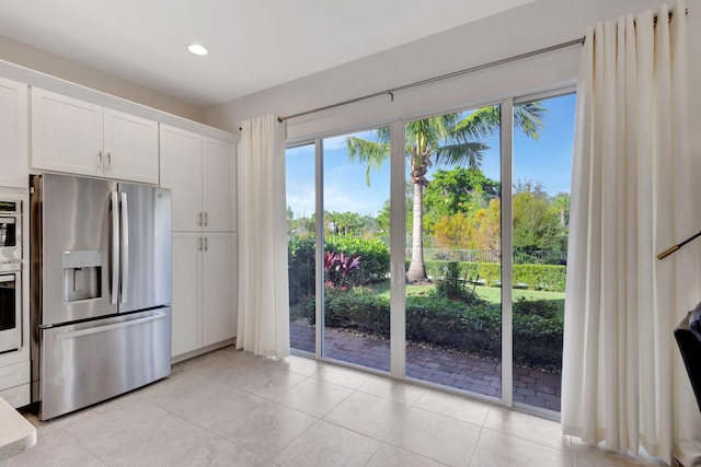 kitchen with white cabinets, appliances with stainless steel finishes, and light tile patterned flooring