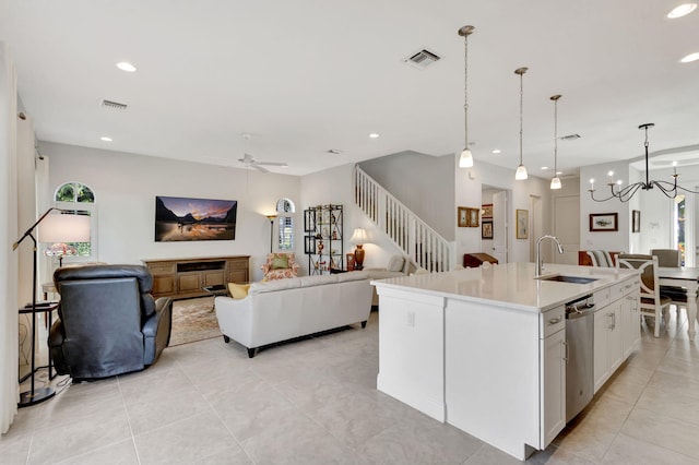 kitchen with white cabinetry, dishwasher, sink, a center island with sink, and ceiling fan with notable chandelier