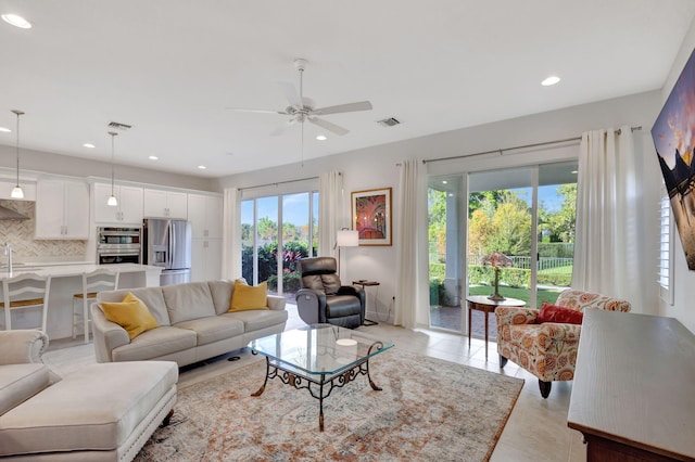 living room with ceiling fan, a healthy amount of sunlight, light tile patterned floors, and sink