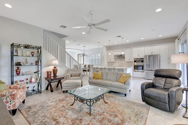 tiled living room with ceiling fan with notable chandelier