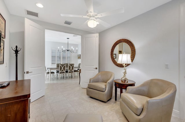 living area with light tile patterned floors and ceiling fan with notable chandelier