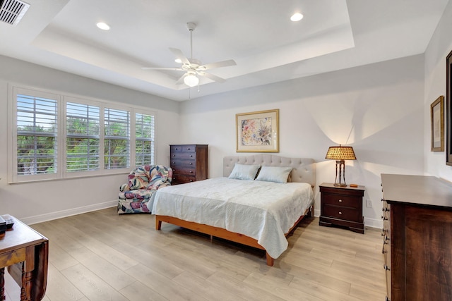 bedroom featuring a tray ceiling, ceiling fan, and light wood-type flooring