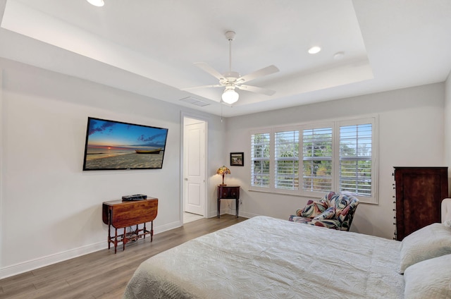 bedroom featuring a tray ceiling, ceiling fan, and wood-type flooring