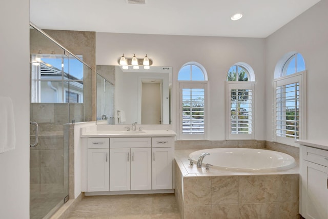 bathroom featuring plus walk in shower, vanity, and plenty of natural light