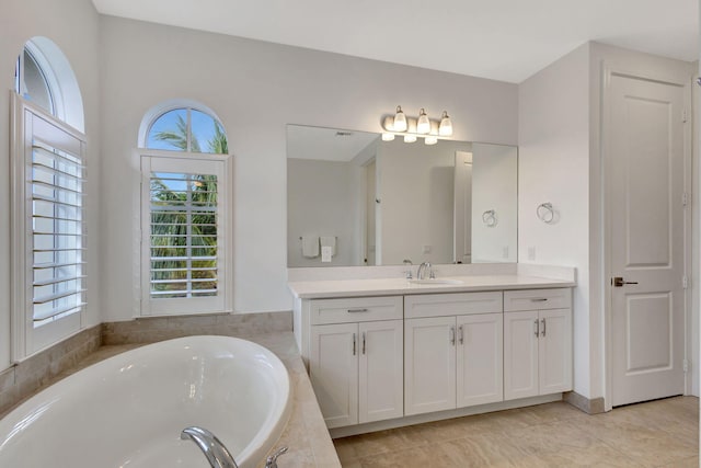 bathroom with tile patterned floors, tiled bath, and vanity