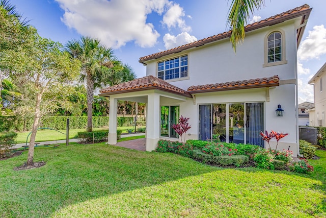 rear view of house featuring a lawn and a patio