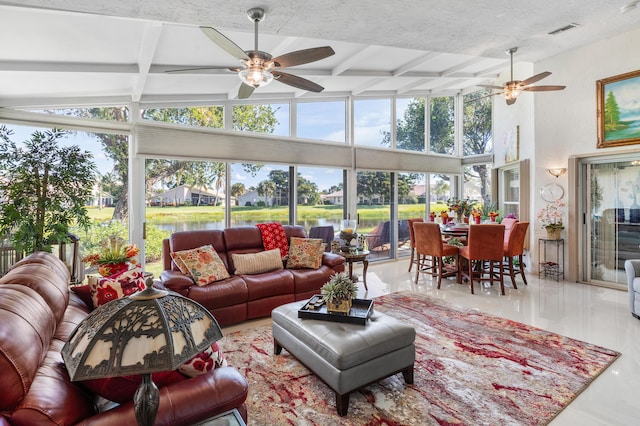 sunroom with ceiling fan, plenty of natural light, and beamed ceiling