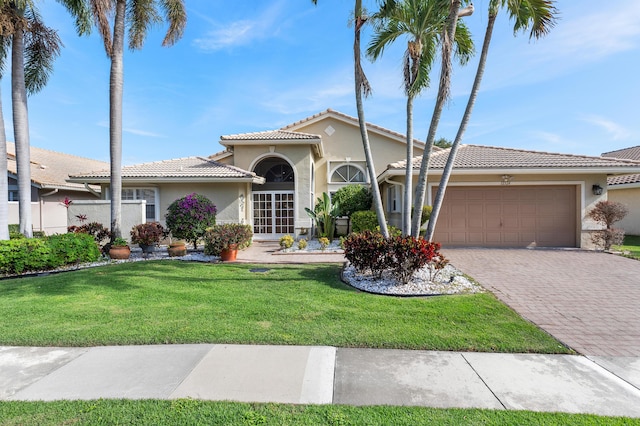 mediterranean / spanish home with a garage and a front lawn