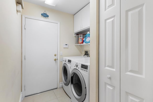 washroom featuring cabinets, light tile patterned floors, and washing machine and clothes dryer